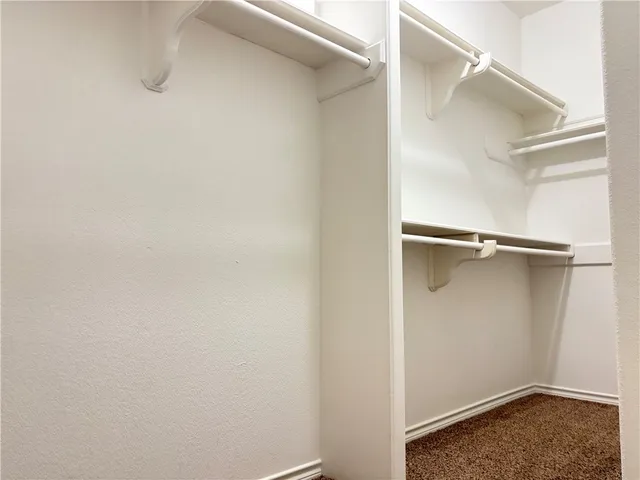 a view of walk in closet with empty racks