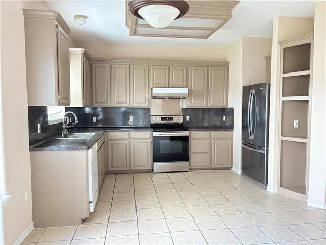 a kitchen with stainless steel appliances granite countertop a stove a sink and a refrigerator