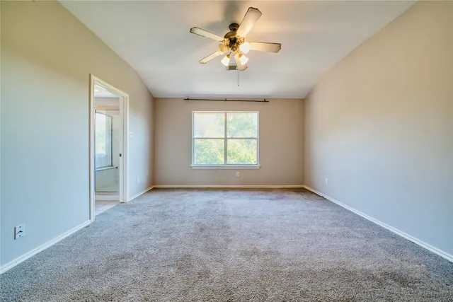 an empty room with windows and ceiling fan
