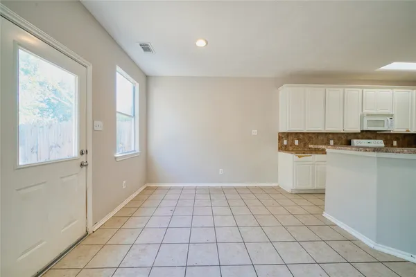 a view of a kitchen with white cabinets and wooden floor
