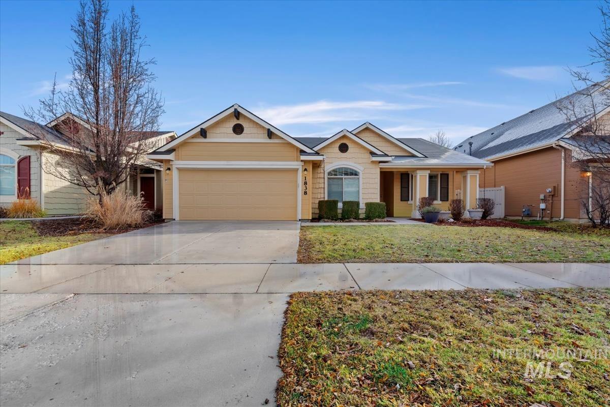 Ranch-style house featuring concrete driveway, an attached garage, a front lawn, and a porch