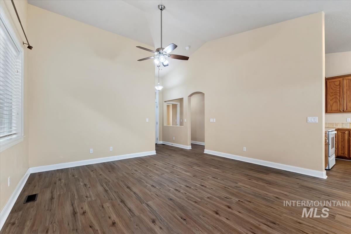 1838 Ridge Way Middleton, ID 83644 - Photo 13 of 42 Empty room featuring dark wood-style floors, ceiling fan, arched walkways, and high vaulted ceiling