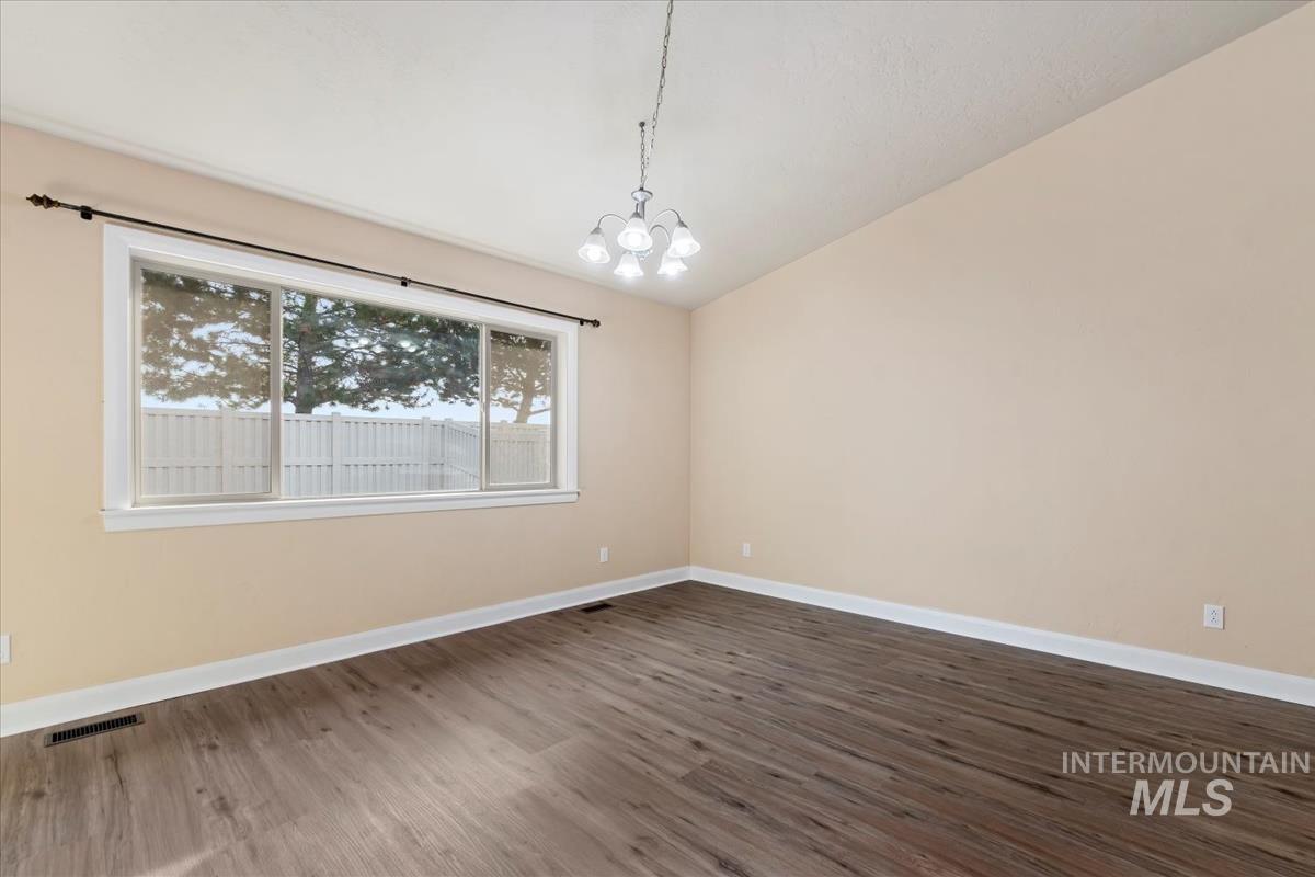 1838 Ridge Way Middleton, ID 83644 - Photo 15 of 42 Spare room featuring lofted ceiling, a chandelier, and dark wood-style flooring