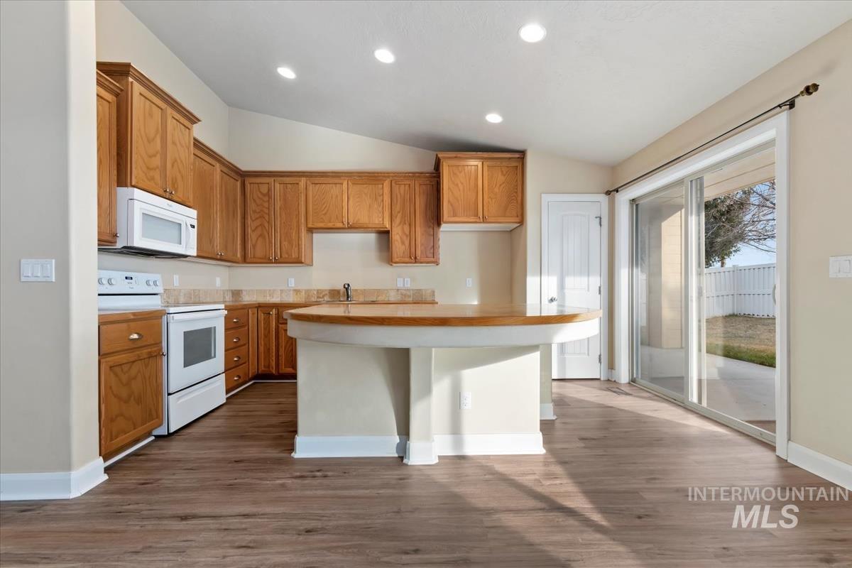 1838 Ridge Way Middleton, ID 83644 - Photo 16 of 42 Kitchen featuring white appliances, light countertops, lofted ceiling, brown cabinetry, and recessed lighting