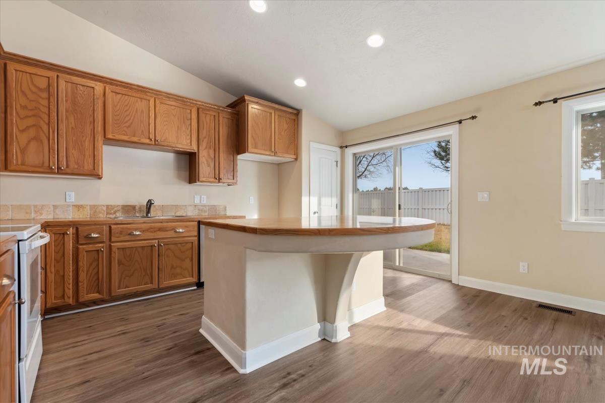 1838 Ridge Way Middleton, ID 83644 - Photo 17 of 42 Kitchen with brown cabinets, electric range, vaulted ceiling, recessed lighting, and light countertops