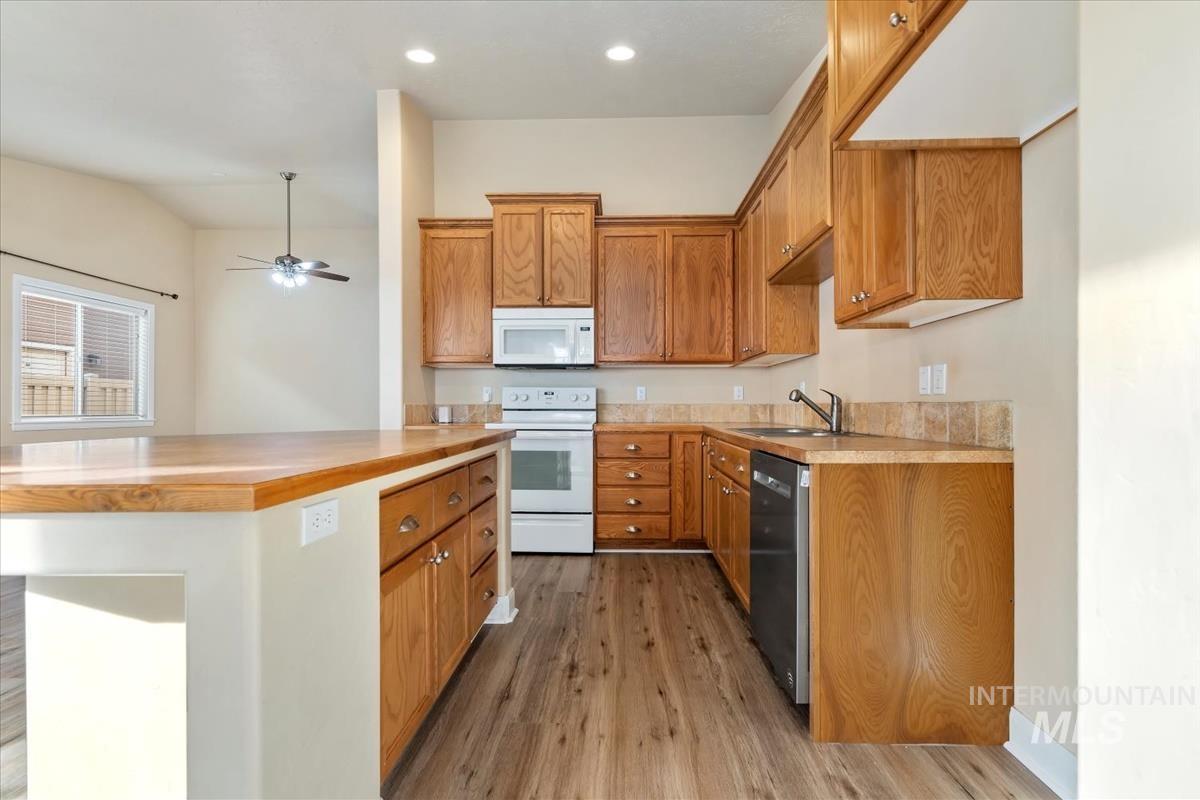 1838 Ridge Way Middleton, ID 83644 - Photo 18 of 42 Kitchen featuring white appliances, light wood-type flooring, brown cabinetry, a center island, and ceiling fan