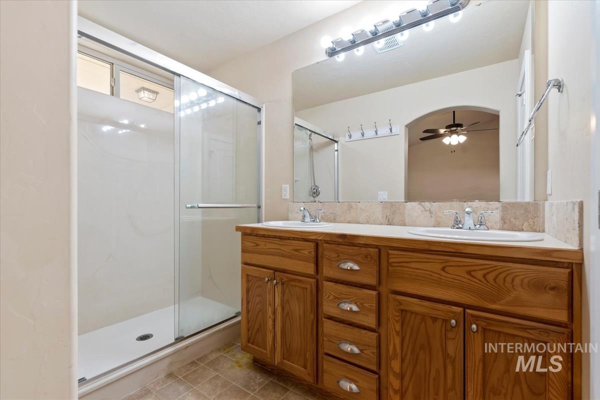 1838 Ridge Way Middleton, ID 83644 - Photo 30 of 42 Full bathroom featuring double vanity, a shower stall, ceiling fan, and light tile patterned floors