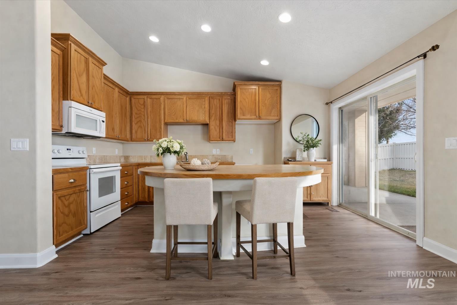 1838 Ridge Way Middleton, ID 83644 - Photo 4 of 42 Kitchen featuring lofted ceiling, white appliances, recessed lighting, a breakfast bar, and dark wood-type flooring