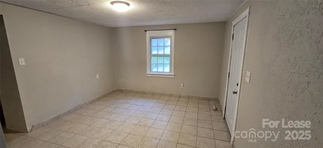 a view of an empty room with window and bathroom