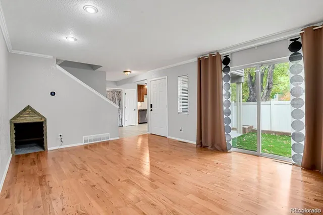 a view of empty room with wooden floor and fan