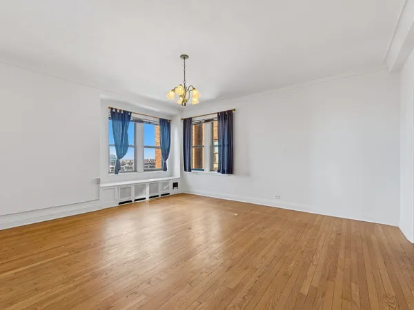 a view of an empty room with window and wooden floor