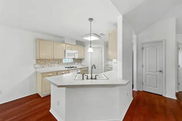 a kitchen with kitchen island granite countertop a sink cabinets and wooden floor