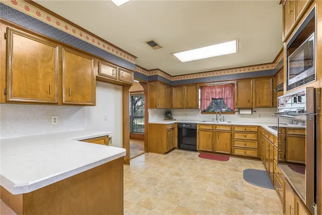 a kitchen with a refrigerator a stove top oven a sink a dining table and chairs