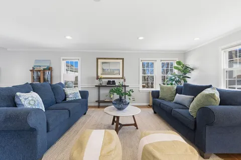 a living room with furniture white walls and a large window