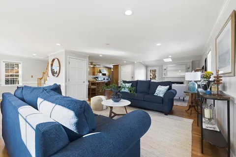 a living room with furniture kitchen view and a wooden floor