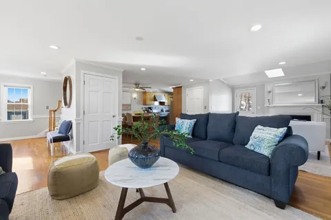 a living room with furniture potted plant and kitchen view
