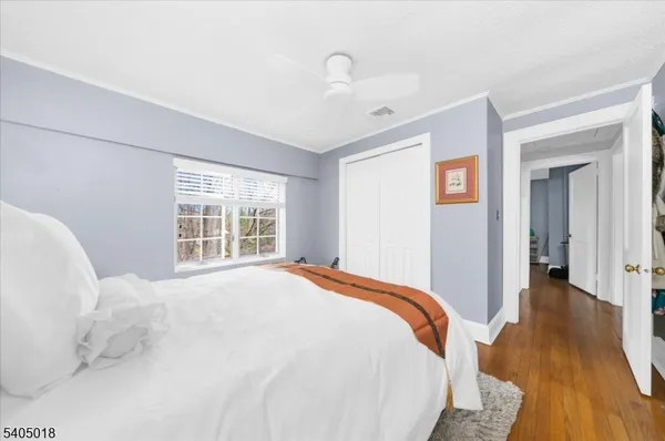 a view of a bedroom with wooden floor and window