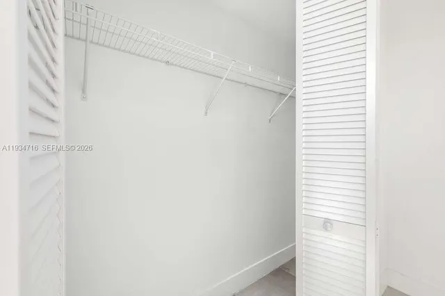 a view of an empty room with a window and cabinet