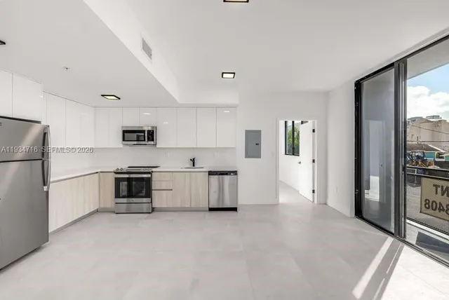 a living room with furniture a rug potted plant and a view of kitchen