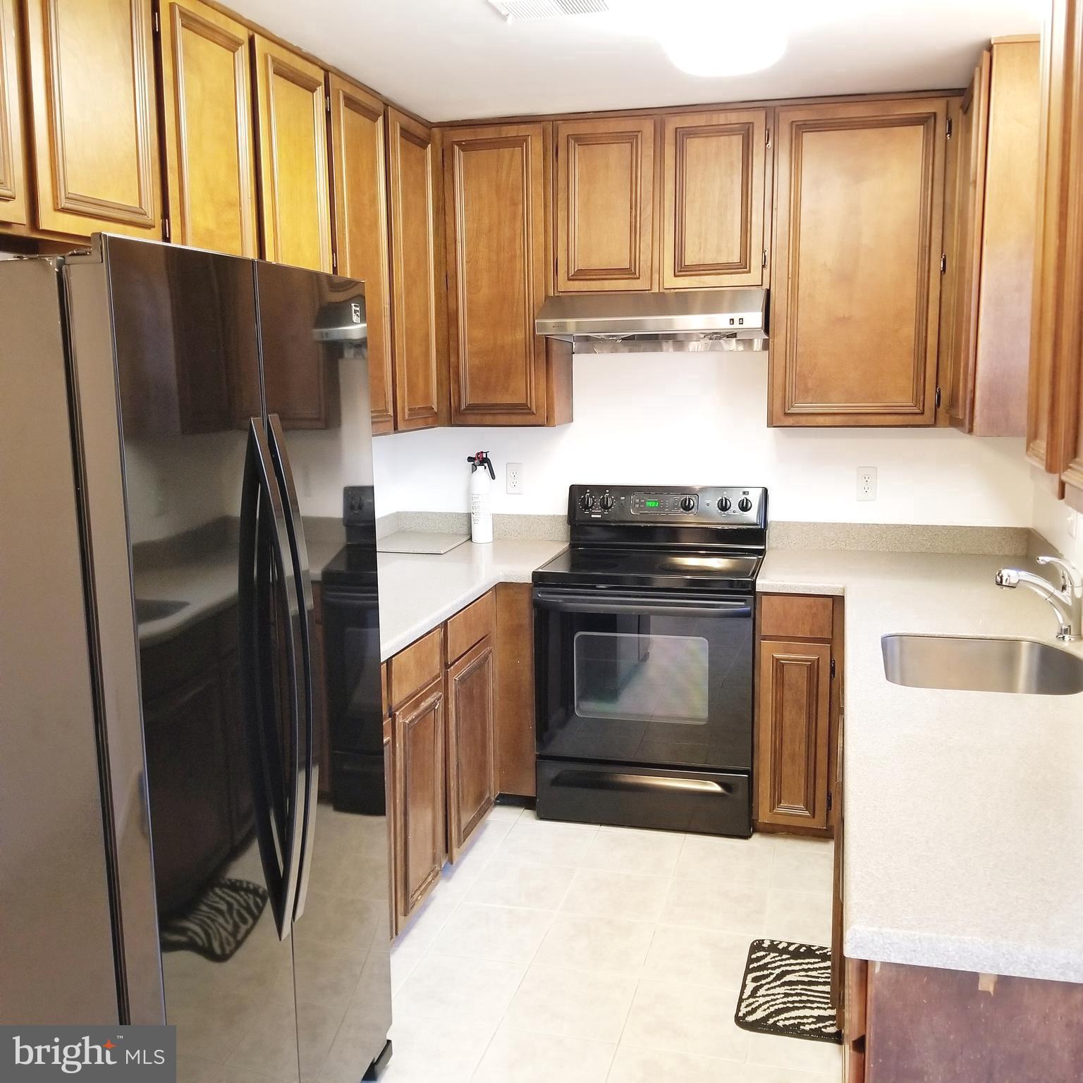 10401 Storch Drive Lanham, MD 20706 - Photo 22 of 28 a kitchen with granite countertop a refrigerator and a stove top oven