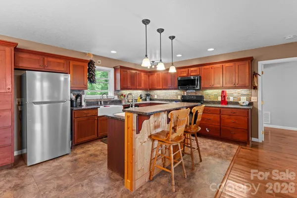 a kitchen with stainless steel appliances a refrigerator a stove a sink dishwasher with a dining table and chairs
