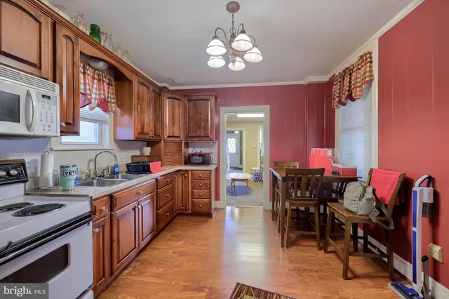 a kitchen with stainless steel appliances granite countertop a stove top oven a sink dishwasher a dining table and chairs with wooden floor