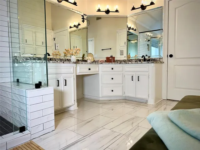 a bathroom with a sink vanity granite tub shower and a mirror