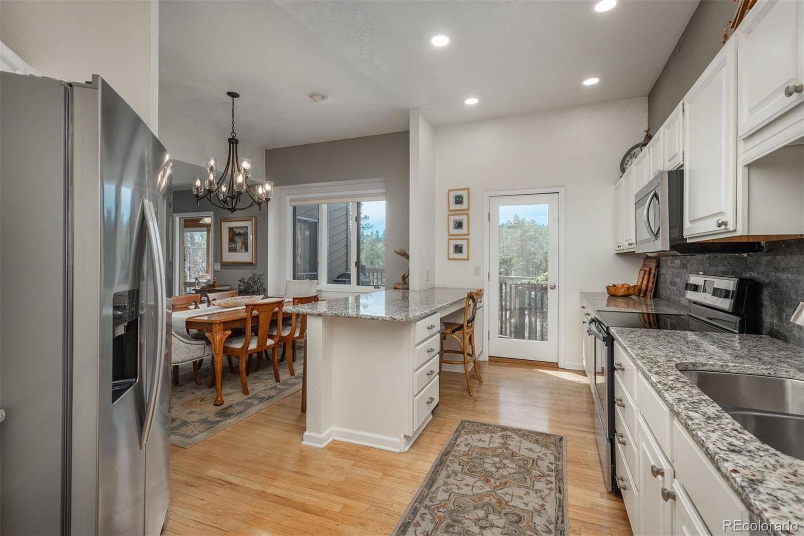 4192 Timbervale Drive Evergreen, CO 80439 - Photo 14 of 50 a kitchen with stainless steel appliances granite countertop a refrigerator a sink dishwasher a stove and a dining table with wooden floor