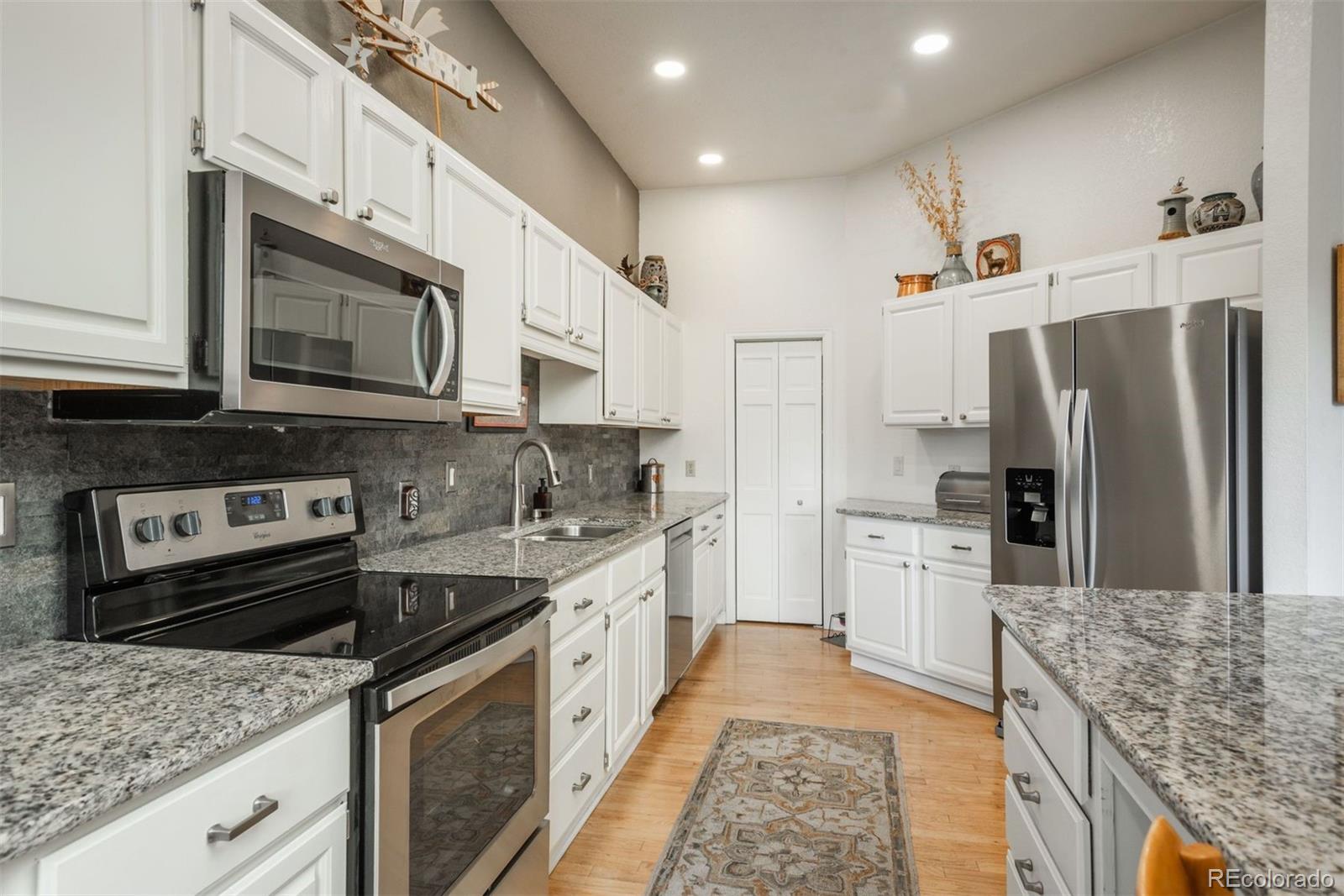 4192 Timbervale Drive Evergreen, CO 80439 - Photo 19 of 50 a kitchen with stainless steel appliances granite countertop a sink stove microwave refrigerator and cabinets
