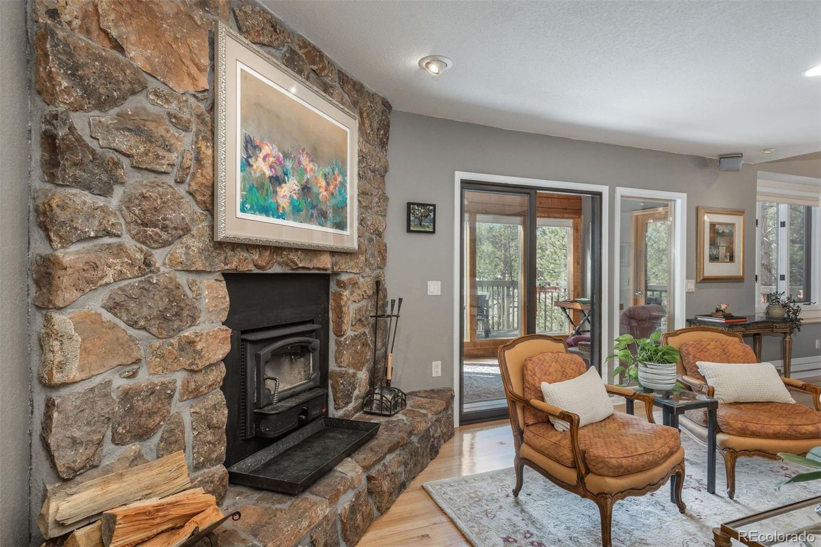4192 Timbervale Drive Evergreen, CO 80439 - Photo 8 of 50 a living room with furniture a fireplace and a floor to ceiling window