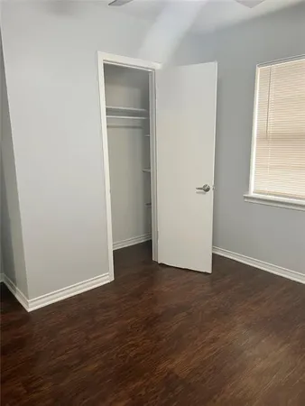 an empty room with wooden floor closet and windows