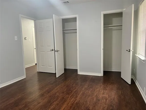 an empty room with wooden floor & closet and windows
