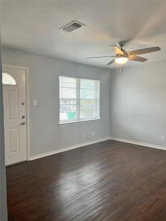 an empty room with wooden floor fan and windows