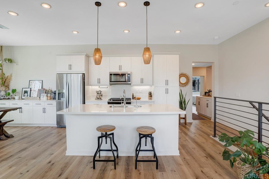 2048 Bravo Loop, Unit 2 Chula Vista, CA 91915 - Photo 5 of 34 a kitchen with stainless steel appliances kitchen island granite countertop a stove a refrigerator and white cabinets with wooden floors