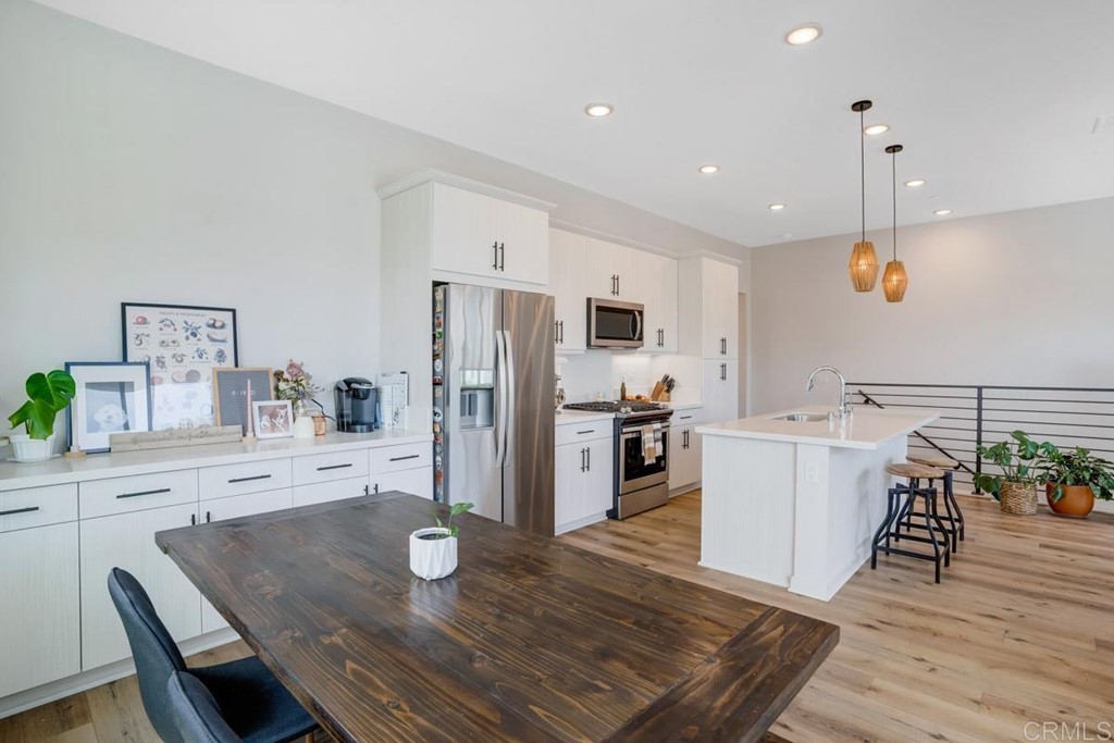 2048 Bravo Loop, Unit 2 Chula Vista, CA 91915 - Photo 10 of 34 a kitchen with stainless steel appliances a dining table chairs and wooden floor