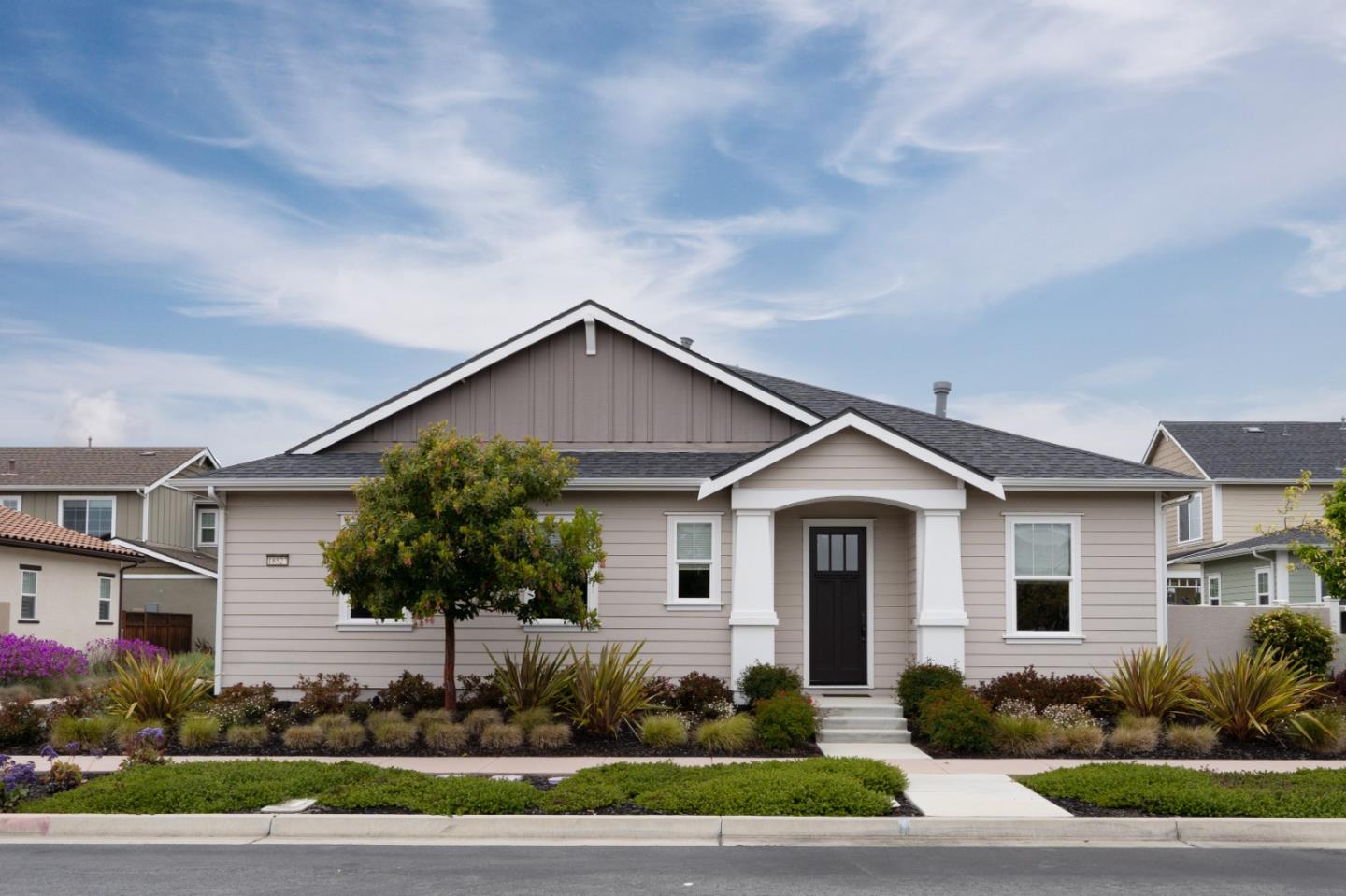 a front view of a house with a yard and potted plants