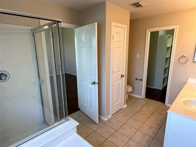 a view of bathroom with a shower and closet