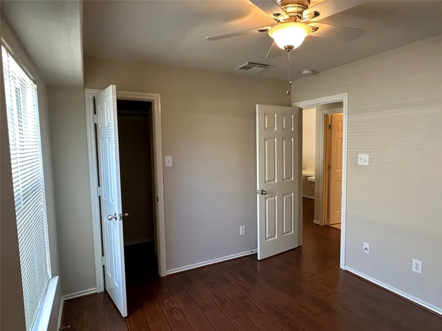 an empty room with wooden floor closet and windows