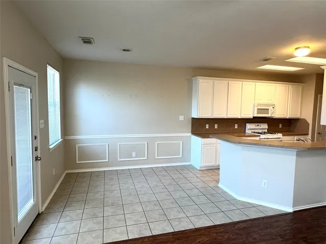 a kitchen with a refrigerator a stove top oven and white cabinets