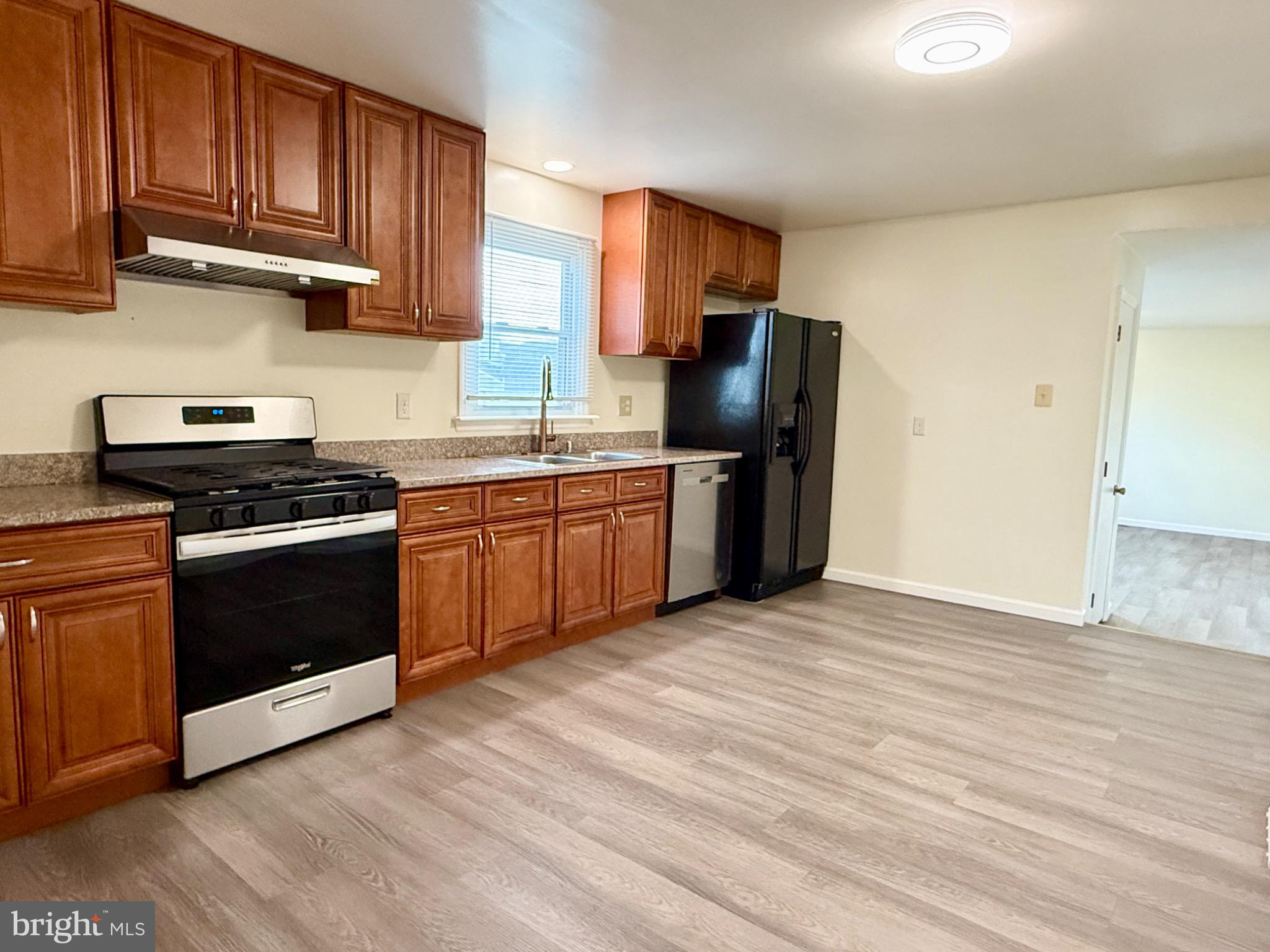 303 Oregon Avenue New Castle, DE 19720 - Photo 13 of 40 a kitchen with stainless steel appliances granite countertop a stove top oven a sink dishwasher and a refrigerator with wooden cabinets