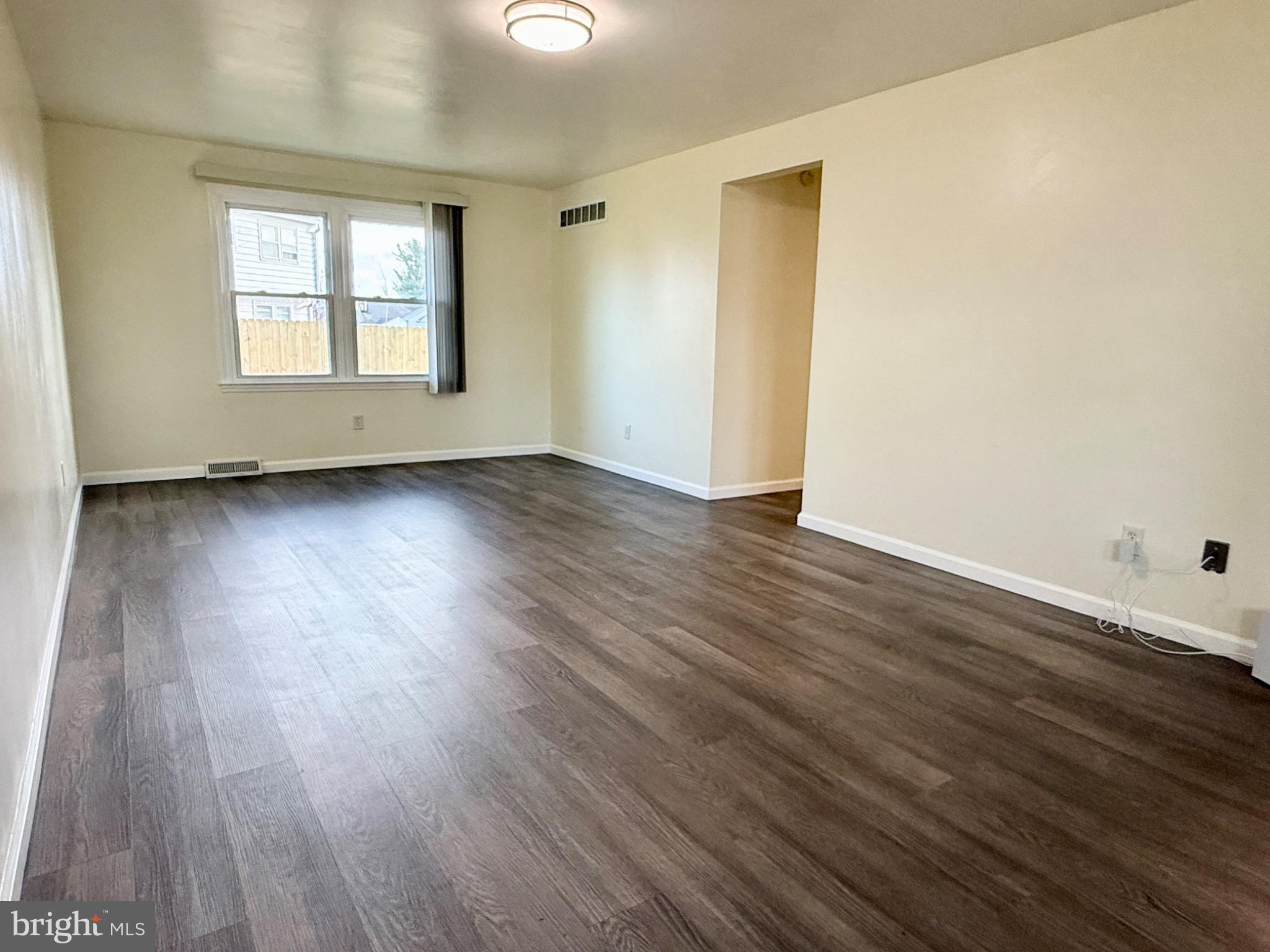 303 Oregon Avenue New Castle, DE 19720 - Photo 6 of 40 an empty room with wooden floor and windows