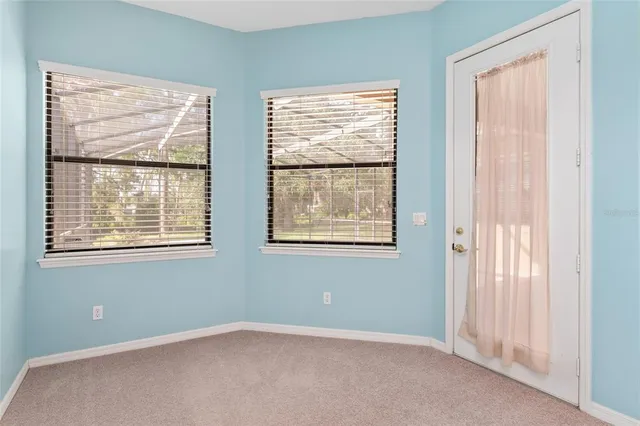 a view of a livingroom with a fireplace a ceiling fan and windows
