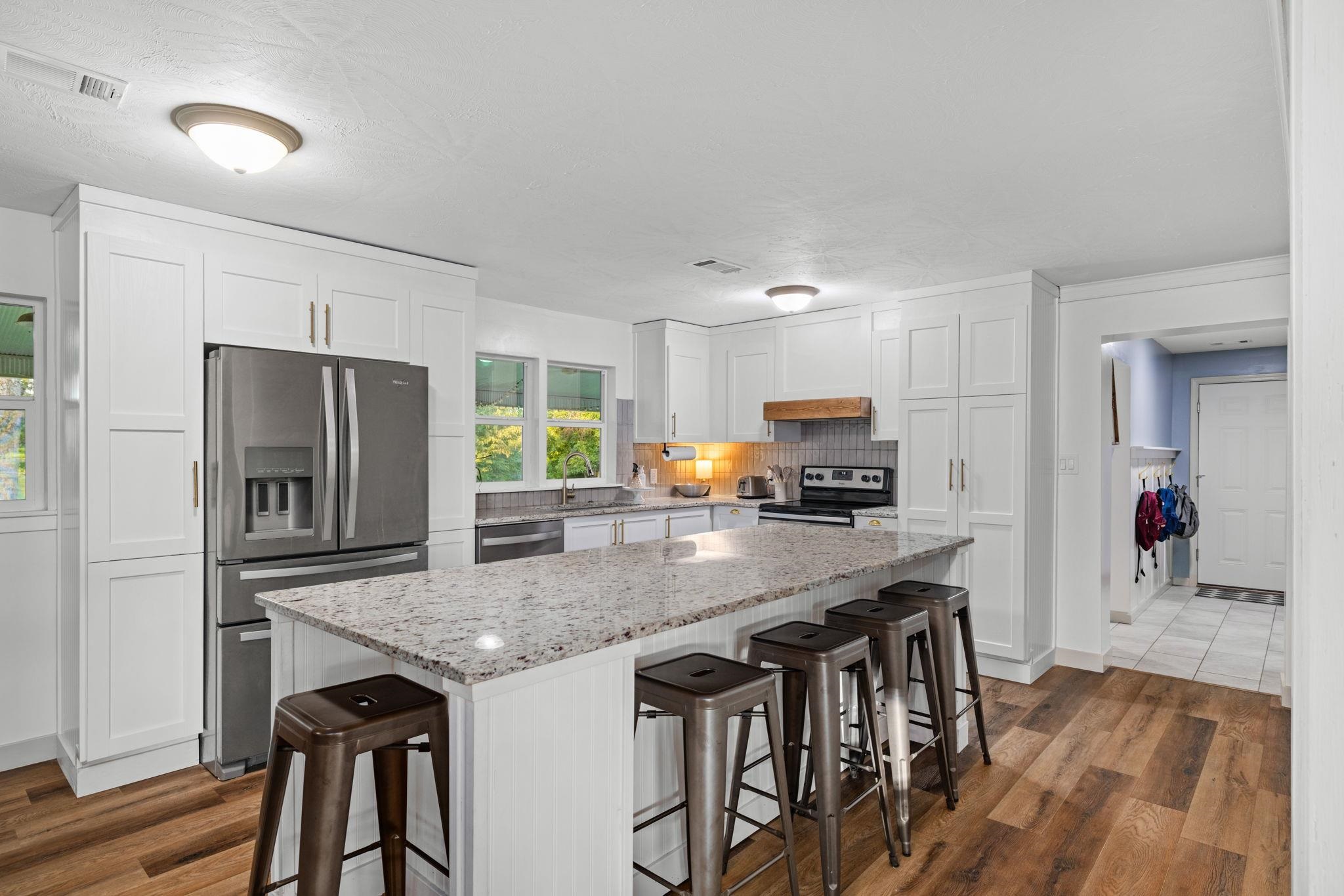66 County Road 511 Corinth, MS 38834 - Photo 9 of 40 Kitchen featuring a central island with granite countertop, white shaker cabinetry, stainless steel appliances, and wood-finish flooring