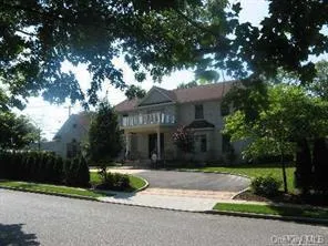a front view of a house with a garden and tree