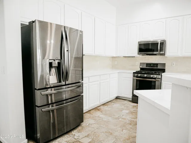 a kitchen with stainless steel appliances white cabinets and a refrigerator