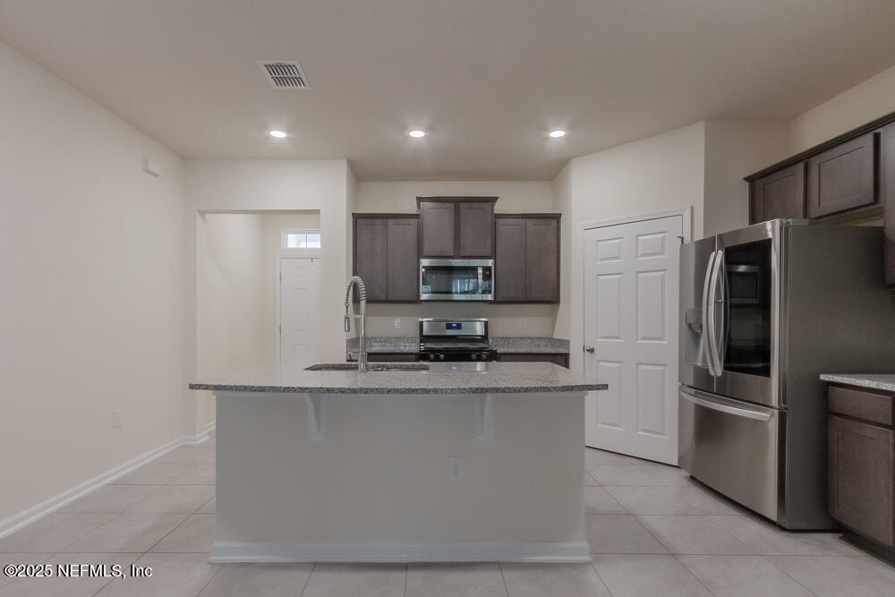 97 Coastline Way Street St. Augustine, FL 32092 - Photo 3 of 31 a kitchen with stainless steel appliances granite countertop a refrigerator a stove a sink and a microwave