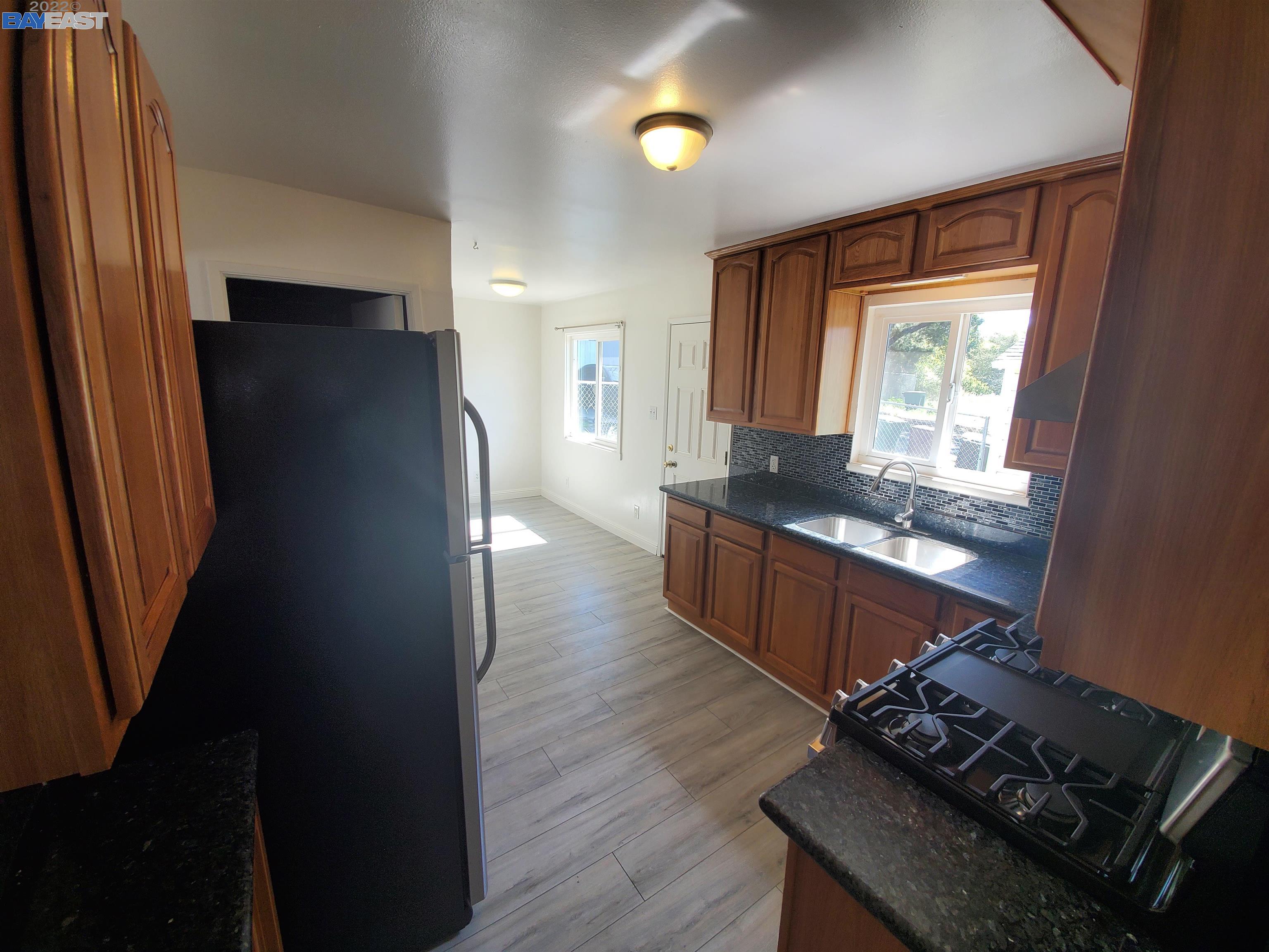 1869 E Street Hayward, CA 94541 - Photo 13 of 22 a kitchen with granite countertop a refrigerator a stove and a sink with wooden floor
