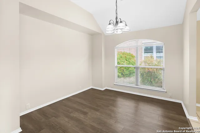 an empty room with wooden floor and kitchen view
