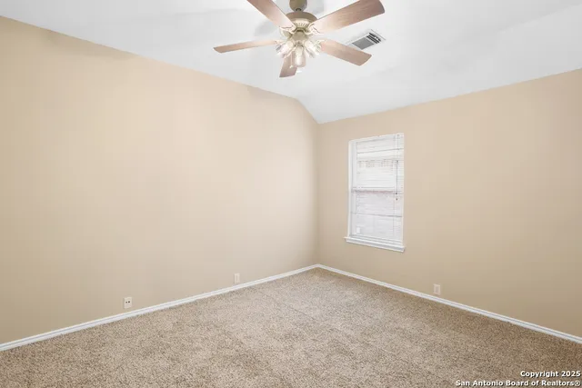 an empty room with a ceiling fan and carpet