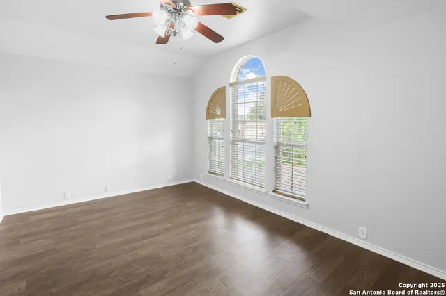 an empty room with wooden floor chandelier fan and closet area